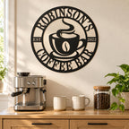 Personalized black metal coffee bar sign above an oak cabinet with an espresso machine, ceramic mugs, and a jar of coffee beans.