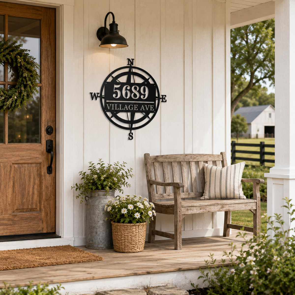Personalized black metal compass address sign displayed on a welcoming American farmhouse porch.