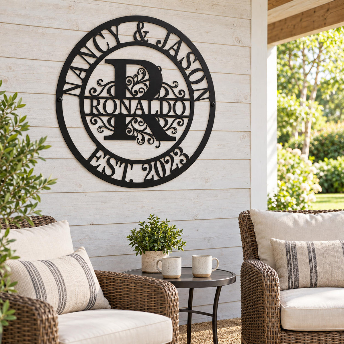 Black metal family monogram sign on a whitewashed wood wall above wicker chairs in a covered patio seating area.