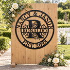 Personalized Nancy & Jason monogram sign on a wooden wedding welcome backdrop decorated with white roses and eucalyptus.