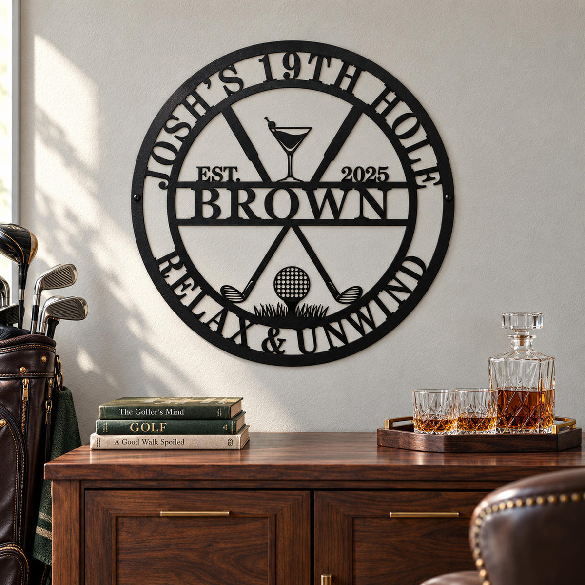 Personalized black metal golf bar sign above a walnut cabinet with a whiskey decanter, glasses, golf books, and a leather golf bag.
