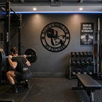 Personalized home gym metal sign displayed on the wall of a modern garage gym.