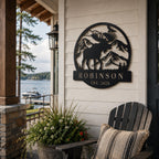 Personalized black metal lake house sign with moose design displayed on outdoor porch wall