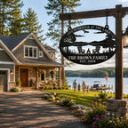 Personalized metal lake house sign suspended by black chains in front of a beautiful lakeside vacation home with a scenic waterfront view.