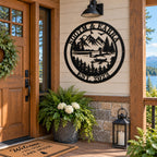 Personalized black metal lake house sign mounted beside the front door of a rustic lakeside cabin.