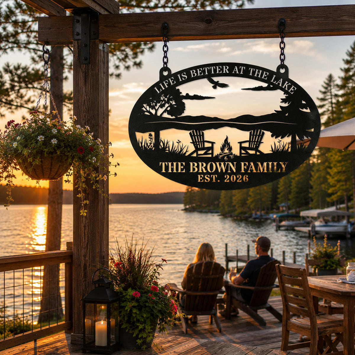 Personalized lake house metal sign hanging from black chains on a wooden beam overlooking a peaceful lakeside deck at sunset.
