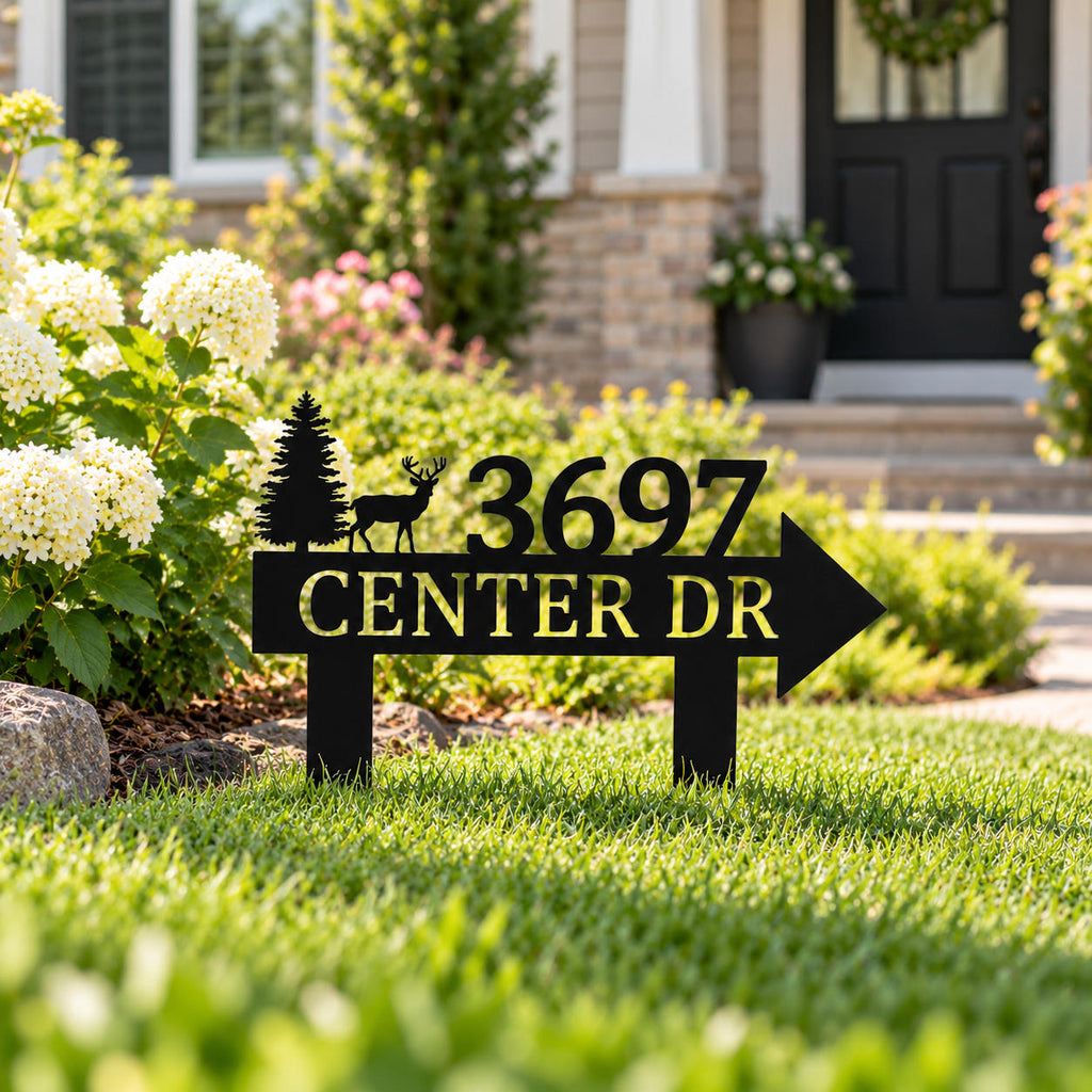 Personalized black metal address sign with directional arrow installed in a landscaped American front yard.