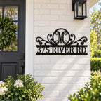 Personalized black metal monogram address sign displayed on a white brick home exterior.