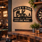 Personalized skeleton metal bar sign mounted in a rustic man cave with a pool table, dartboard, and home bar.