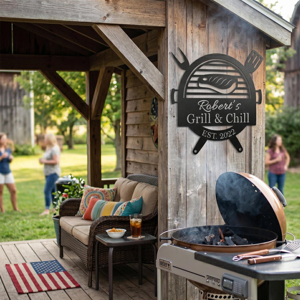 Customized metal BBQ grill name sign featuring a laser-cut steak and grill design, personalized with "Robert's Grill & Chill" and "Est. 2022" on a white brick wall.