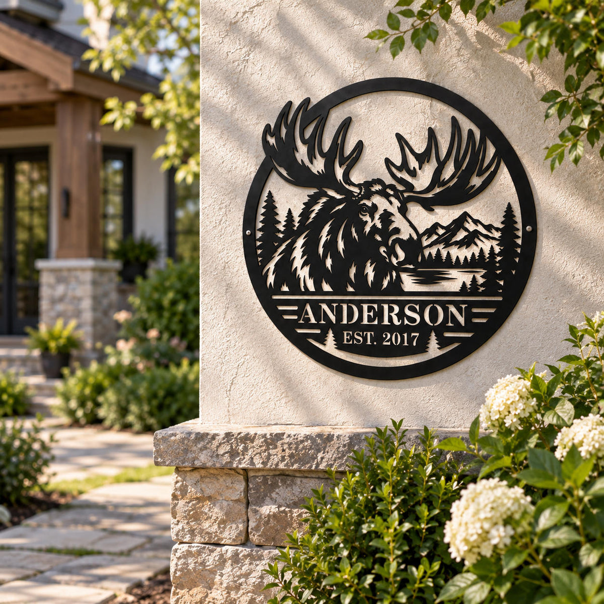 Personalized moose family metal sign displayed at a welcoming home entrance surrounded by stone and garden greenery.