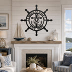 Personalized ship wheel metal wall decor above a fireplace in a coastal living room, custom nautical family name sign for beach house interiors.