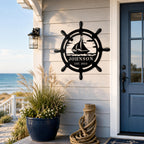 Personalized nautical ship wheel metal sign mounted on the exterior wall of a coastal beach house with custom text.