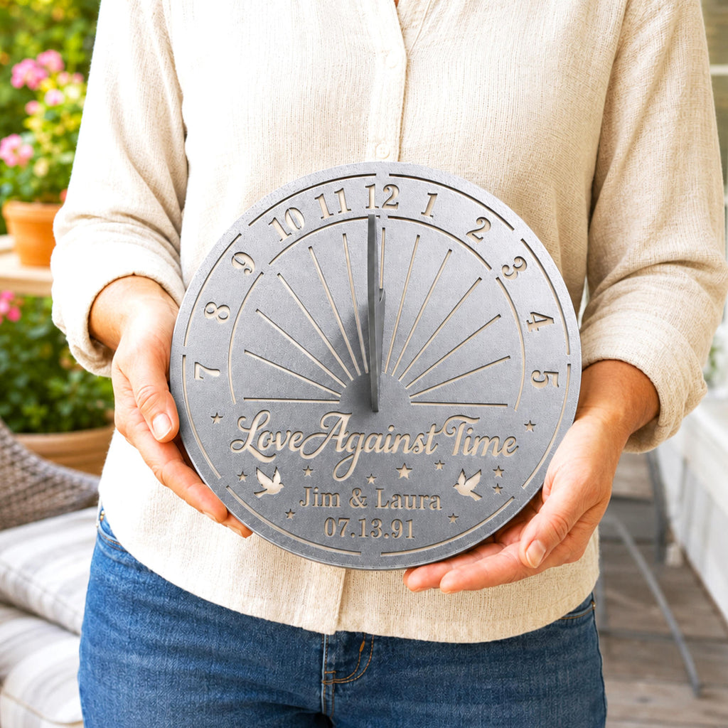 Personalized silver metal sundial held by hand to demonstrate its size and custom engraved names and date.