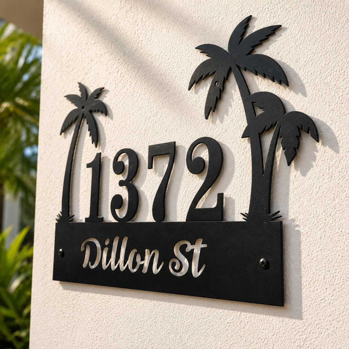 Close-up of a personalized tropical palm tree metal address sign showing hidden mounting holes in the palm tree crown and leaf for a clean installation.