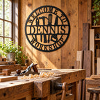 Black Dennis workshop sign on a timber wall in a sunlit woodworking studio with a hand plane, wood shavings, and stacked lumber.
