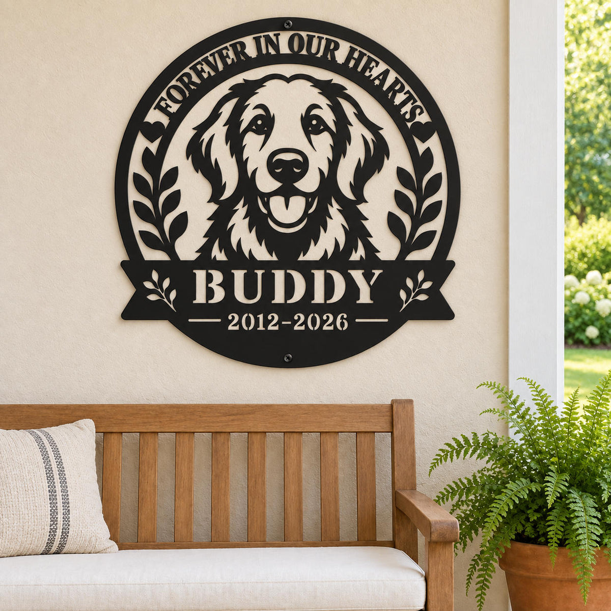 Black metal golden retriever memorial sign for Buddy on a beige covered porch wall above a wooden bench beside a potted fern.