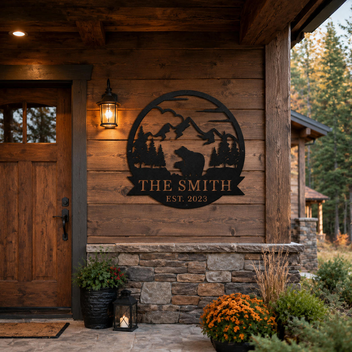 Custom black metal family sign installed on a rustic cabin entrance wall with mountain forest background